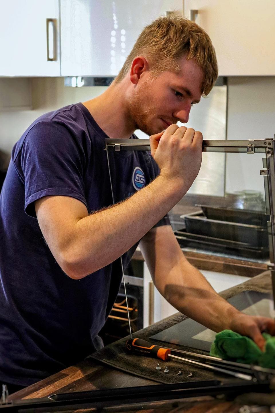 GS Appliance technician cleaning an oven in a customer's kitchen